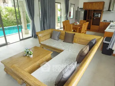 Spacious living room with pool view, wooden furniture, and open kitchen layout in modern home.