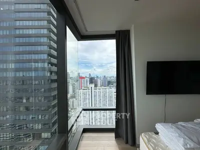 Stunning city view from modern high-rise apartment bedroom with floor-to-ceiling windows.