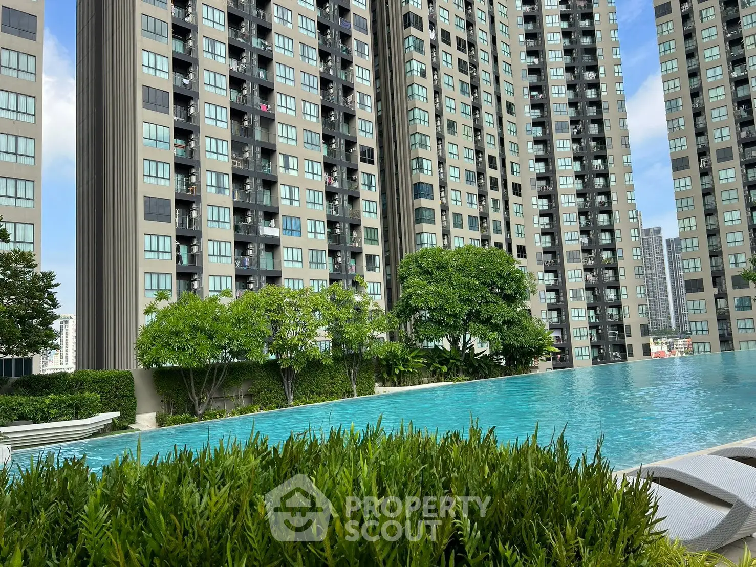 Luxurious high-rise apartment complex with stunning pool and lush greenery, perfect for urban living.
