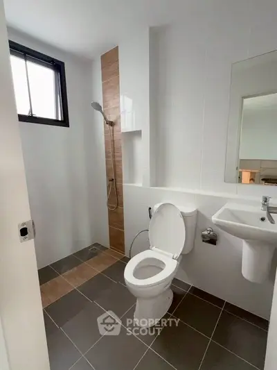 Modern bathroom with sleek design, featuring a shower and toilet in a minimalist setting.