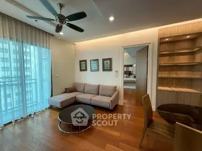 Modern living room with wooden floors, cozy sofa, and ceiling fan in a stylish apartment.