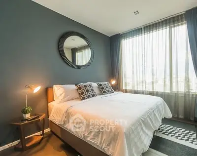 Modern bedroom with stylish decor and large window offering natural light.