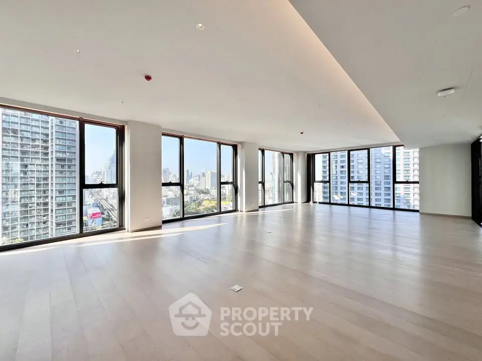 Spacious modern living room with panoramic city views and floor-to-ceiling windows.