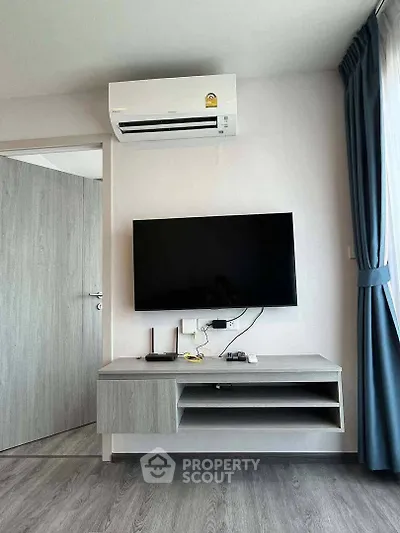 Modern living room with wall-mounted TV and air conditioning unit, featuring sleek furniture and elegant curtains.