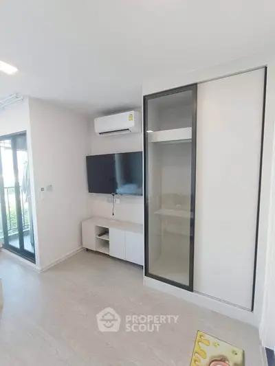 Modern living room with sleek TV setup and sliding closet doors, featuring a bright and airy atmosphere.