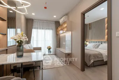 Modern open-plan living room with elegant decor and a glimpse into a cozy bedroom.