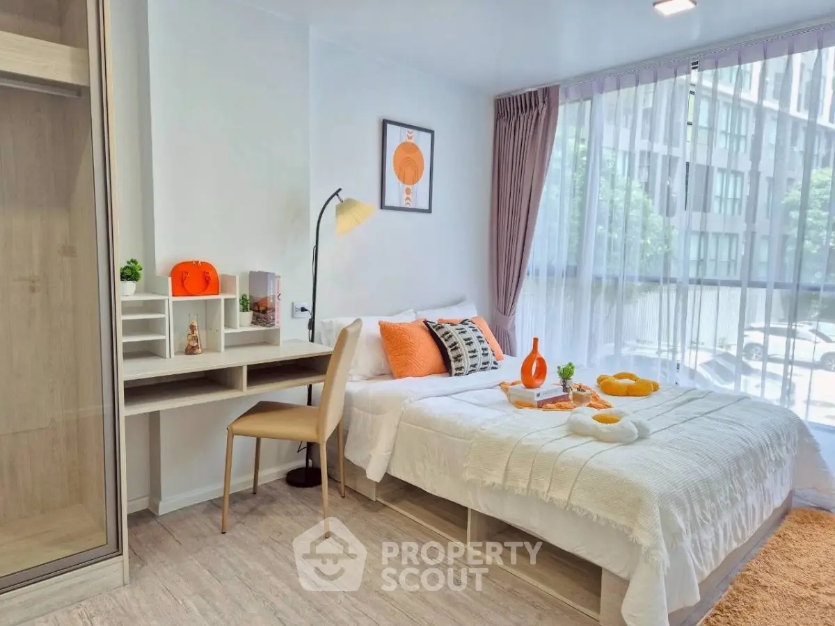 Modern bedroom with stylish decor and large window offering natural light and city view.