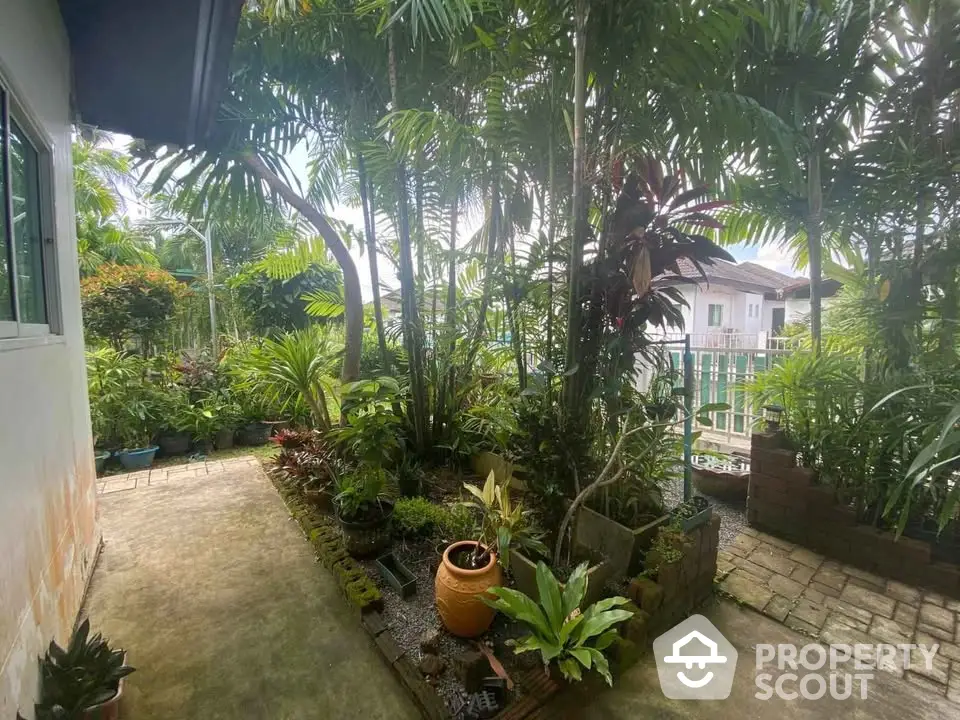 Charming garden view with lush greenery and paved walkway in residential area.