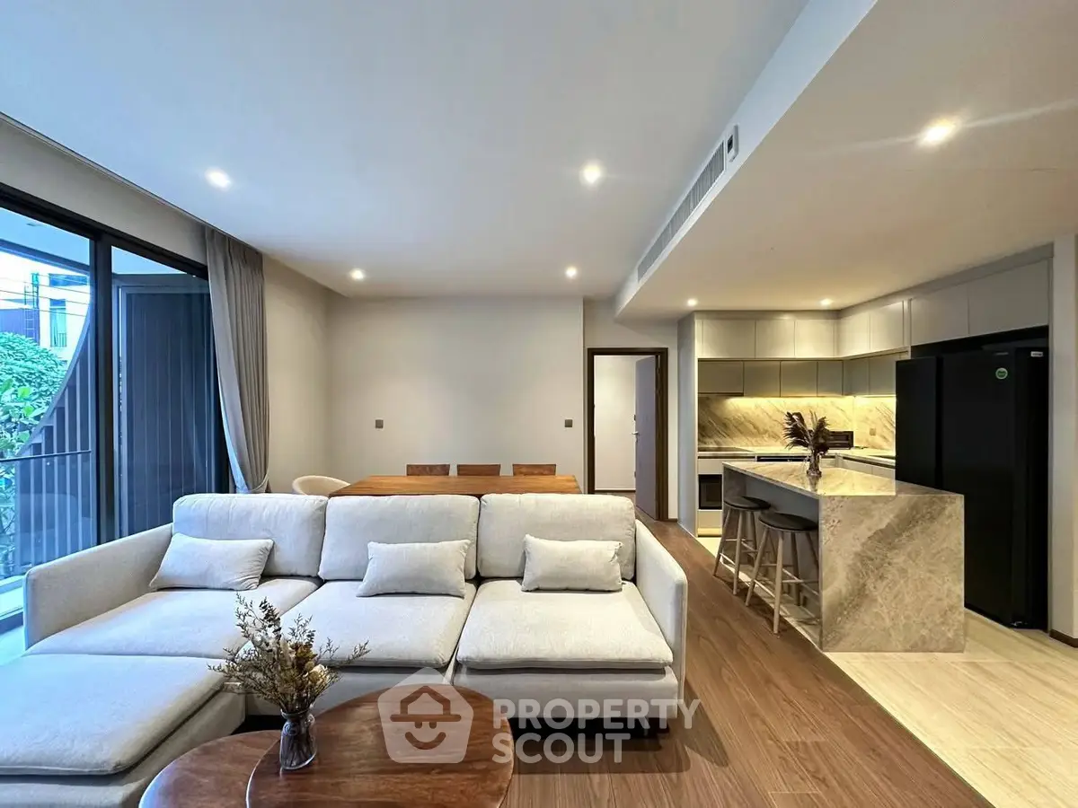 Modern open-layout living room with stylish kitchen and cozy seating area, perfect for entertaining.