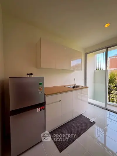 Modern kitchen with sleek cabinets and compact fridge in bright apartment