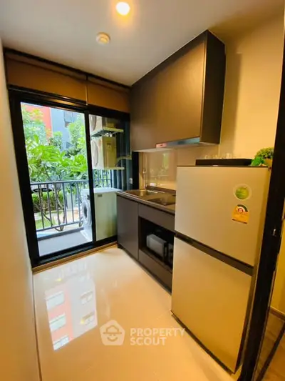 Modern compact kitchen with balcony view, featuring sleek appliances and stylish cabinetry.
