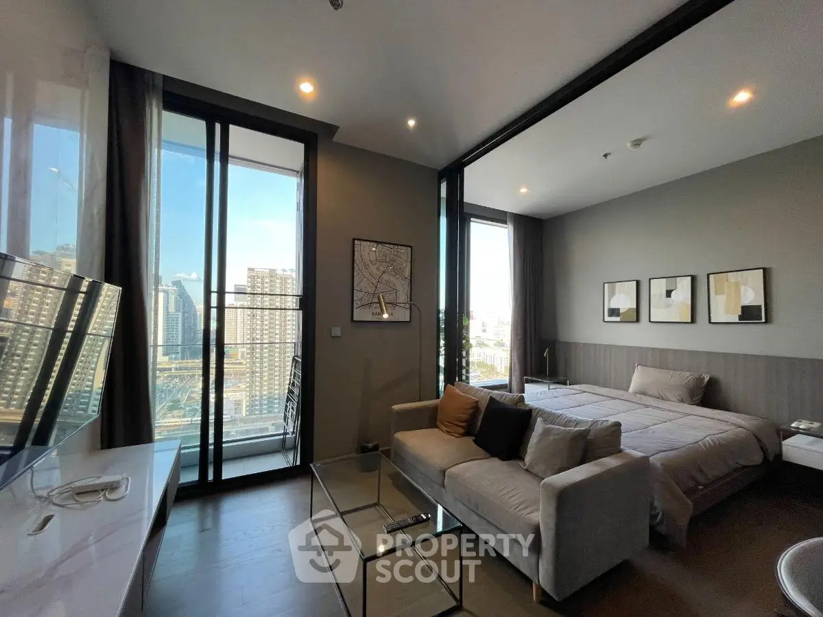 Modern studio apartment with city view, featuring a cozy living area and large windows for natural light.