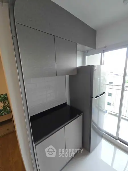 Modern kitchen with sleek cabinets and large fridge in a bright apartment