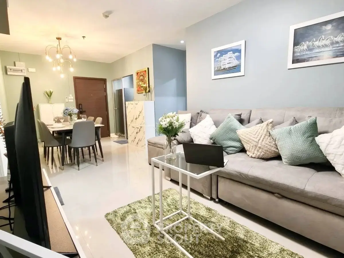 Modern living room with elegant decor and open dining area, featuring plush sofa and stylish lighting.