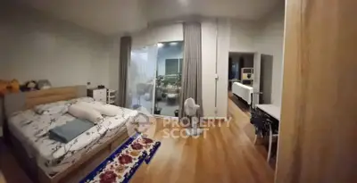 Spacious bedroom with wooden flooring and large glass doors leading to a cozy balcony.