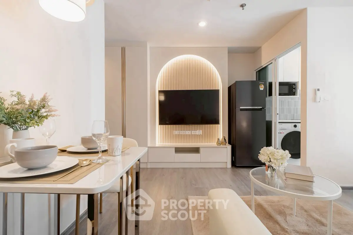 Modern living room with stylish decor and open kitchen layout, featuring a sleek TV setup and elegant dining area.