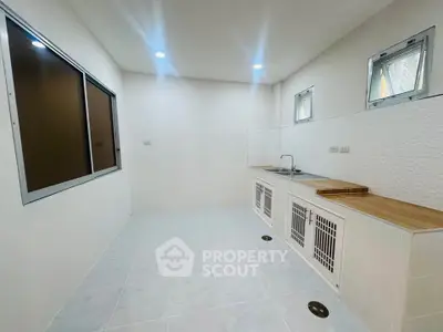 Spacious kitchen with modern design and ample natural light, featuring sleek countertops and minimalist cabinetry.