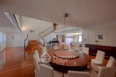 Luxurious dining room with elegant round table and grand staircase in a spacious open layout.