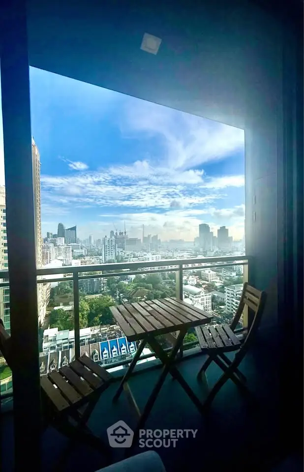 Stunning cityscape view from a high-rise balcony with outdoor seating, perfect for relaxation.