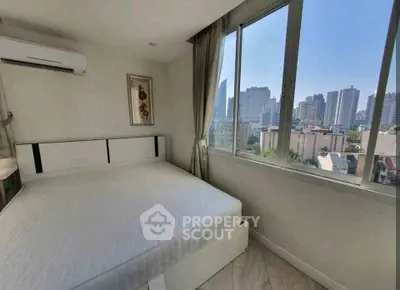 Bright bedroom with large windows offering stunning city views in modern apartment.