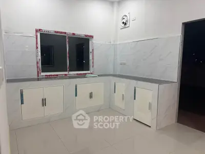 Modern kitchen with sleek white cabinets and tiled backsplash, featuring a minimalist design and ample counter space.