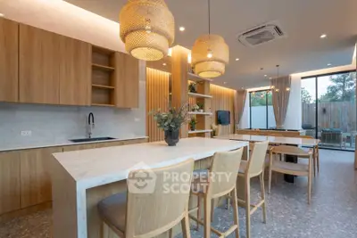 Modern open kitchen with island, wooden cabinets, and stylish lighting in a spacious living area.