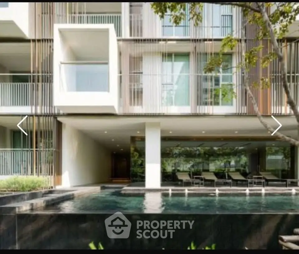 Modern apartment building with pool and stylish balconies in lush surroundings.