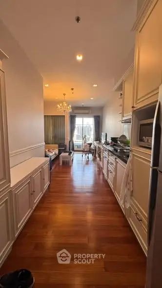 Spacious open-layout kitchen with elegant cabinetry and hardwood floors leading to a cozy living area.