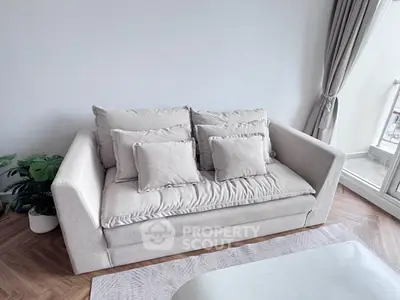 Cozy living room with plush sofa and natural light from balcony.