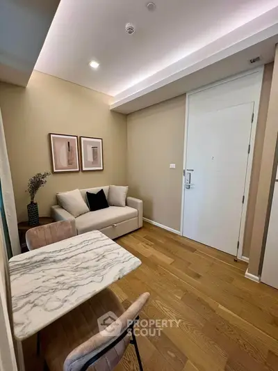 Modern living room with stylish decor and wooden flooring, featuring a cozy sofa and elegant marble table.