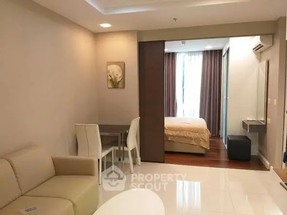 Modern open-plan living room with elegant decor and cozy bedroom view.