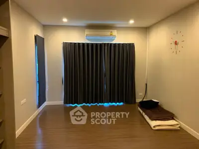 Spacious empty room with wooden flooring and air conditioning, ideal for customization.