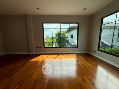 Spacious room with large windows and polished wooden floors, offering abundant natural light.