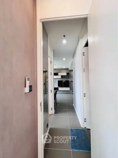 Modern apartment hallway leading to a stylish living area with sleek furnishings and contemporary design.
