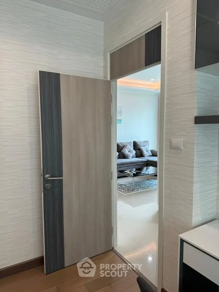 Modern interior with open door leading to stylish living room featuring contemporary furniture and elegant decor.