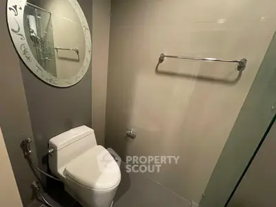 Modern bathroom with sleek toilet and stylish round mirror, perfect for contemporary living.