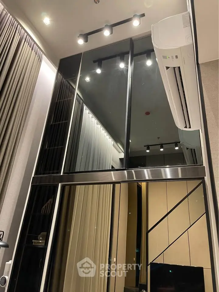 Modern high-ceiling interior with sleek glass panels and air conditioning unit