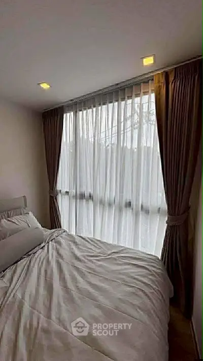 Cozy bedroom with large window and elegant curtains, perfect for natural light lovers.
