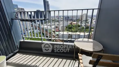 Stunning city view from a high-rise balcony with modern railing and cozy seating area.