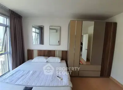 Spacious bedroom with large windows and modern wardrobe in a high-rise apartment.