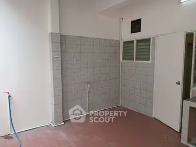 Spacious utility area with tiled walls and plumbing fixtures, ideal for laundry setup.