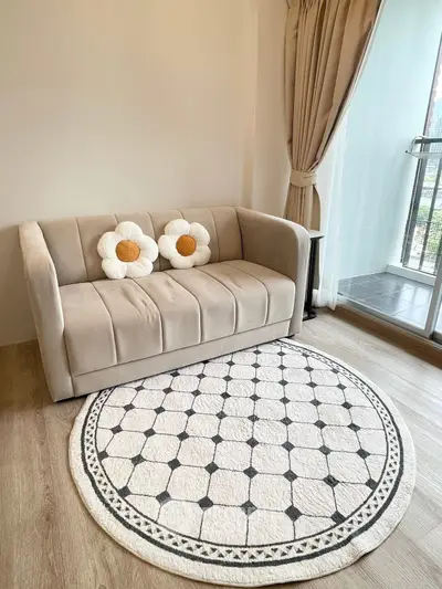 Cozy living room with plush sofa and floral cushions, elegant round rug, and balcony view.