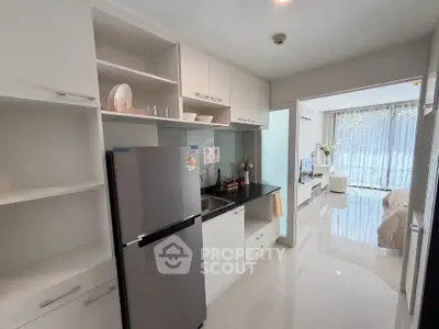 Modern kitchen with sleek appliances and open layout leading to a bright living room.