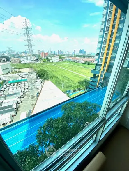 Stunning cityscape view from high-rise apartment window with lush greenery and urban skyline.