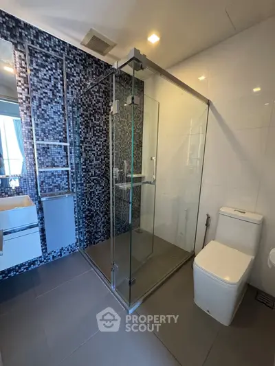 Modern bathroom with glass shower enclosure and stylish mosaic tiles