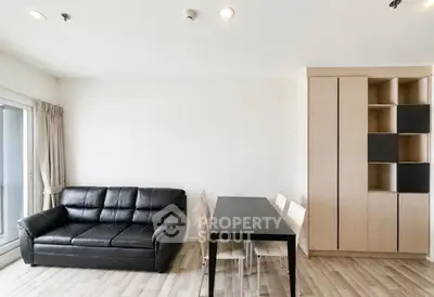 Modern living room with sleek black sofa and dining area in minimalist apartment.