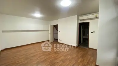 Spacious empty room with wooden flooring and air conditioning unit
