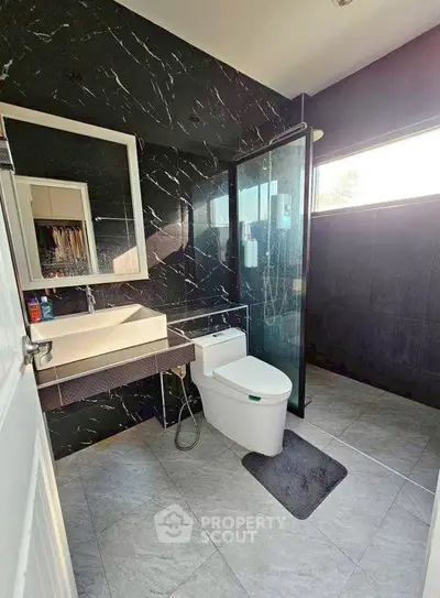 Modern bathroom with sleek black tiles and glass shower enclosure