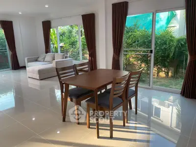 Spacious living room with modern furniture and large windows overlooking lush greenery.