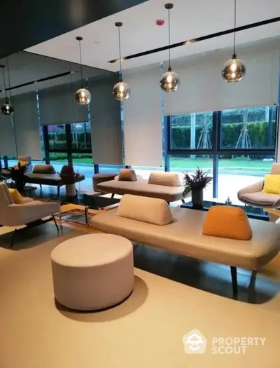 Chic modern living room with sleek furniture and stylish pendant lights, overlooking a serene outdoor pool area through floor-to-ceiling windows.